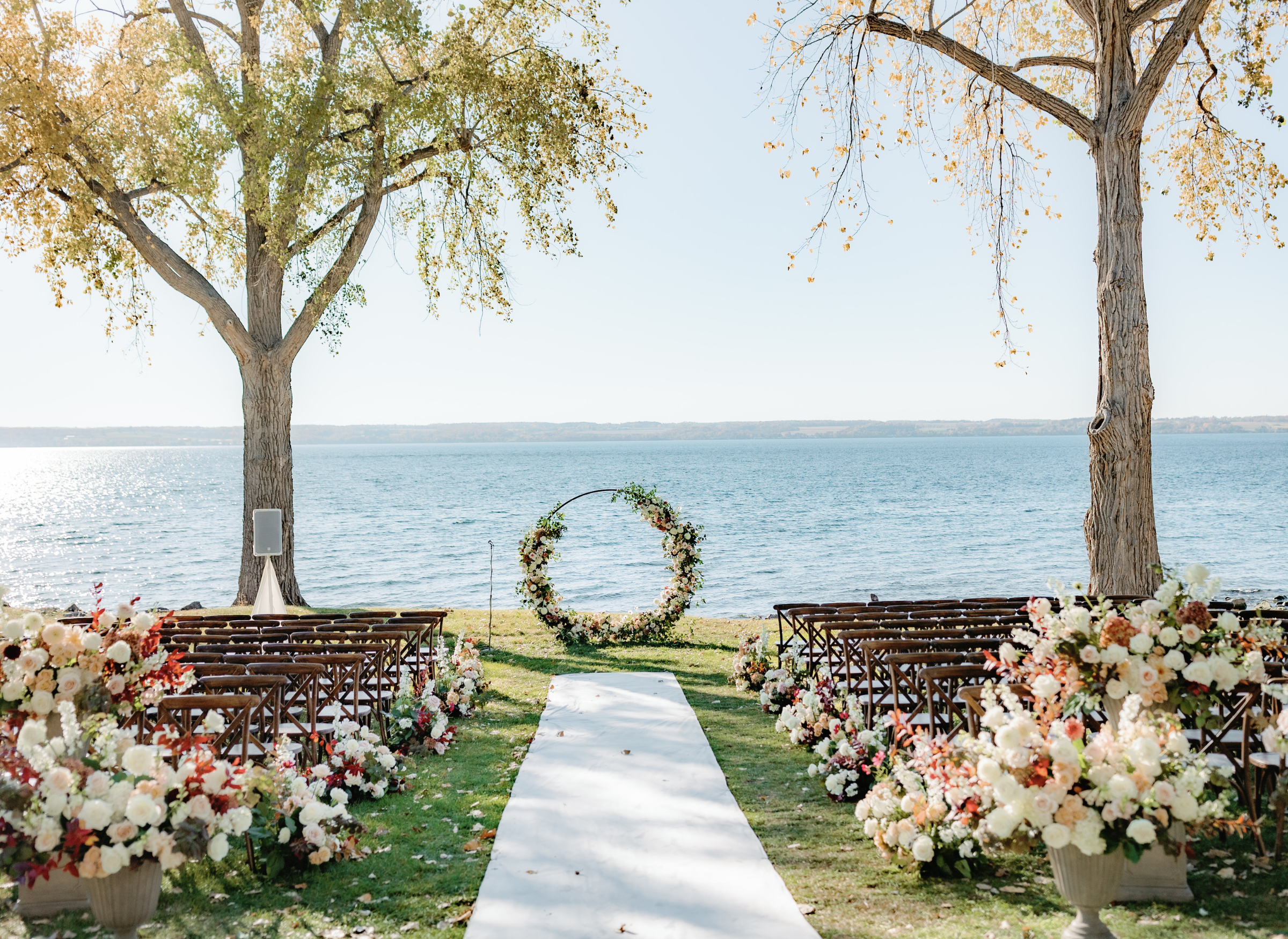 Outdoor wedding ceremony in upstate new york with white aisle runner and brown chairs