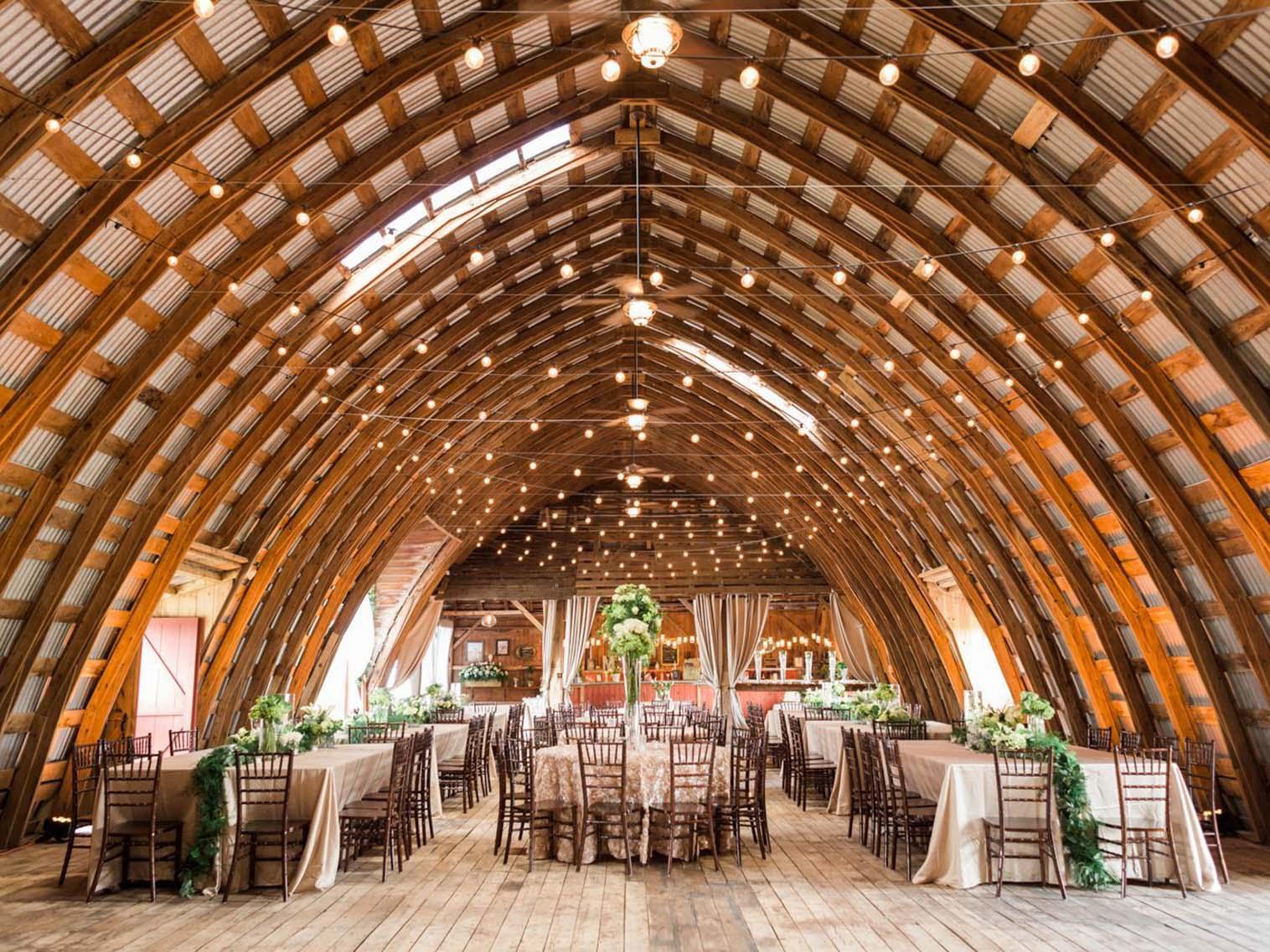 Barn wedding in Upstate New York with white tablecloths and wooden chairs