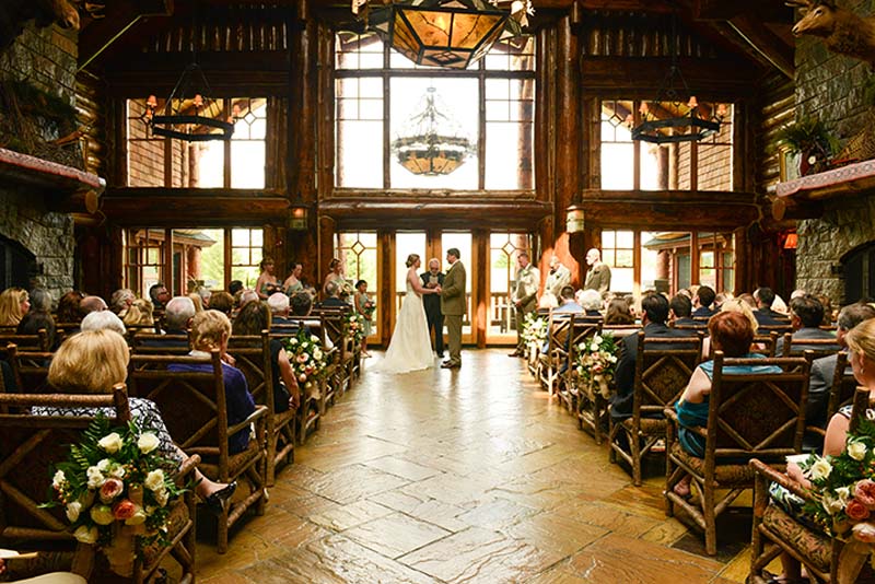 Indoor lake placid wedding ceremony with bride and groom at center aisle at the whiteface lodge